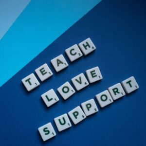 Letter tiles spelling 'Teach Love Support' on blue shaded background, conveying a message of encouragement.
